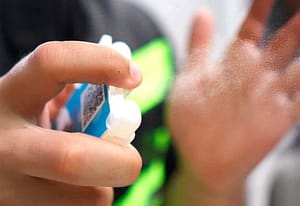 Pessoa utilizando crachá com higienizador para a higienização das mãos